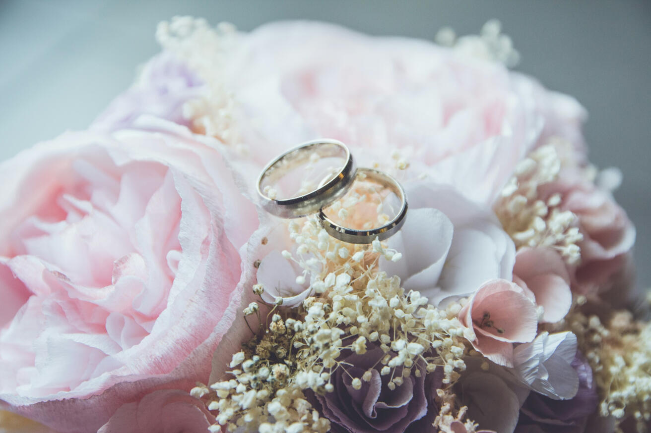 Photo by Beatriz Pérez Moya on Unsplash gold colored bridal ring set on pink peony flower bouquet
